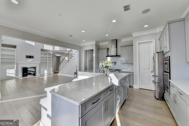 kitchen with wall chimney exhaust hood, visible vents, gray cabinets, and ornamental molding