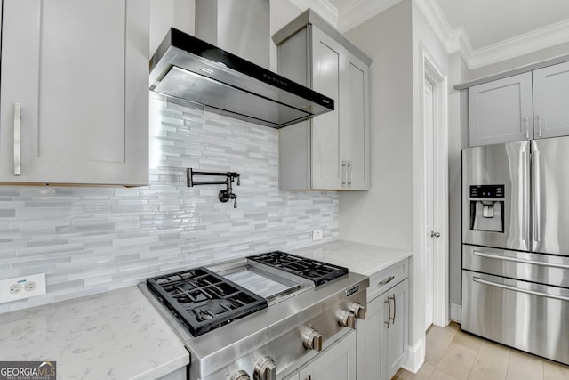 kitchen featuring light stone counters, wall chimney range hood, stainless steel refrigerator with ice dispenser, tasteful backsplash, and crown molding