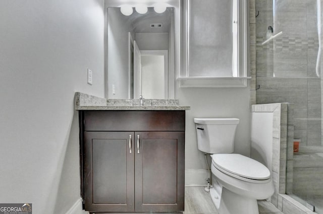 bathroom featuring a stall shower, baseboards, vanity, and toilet