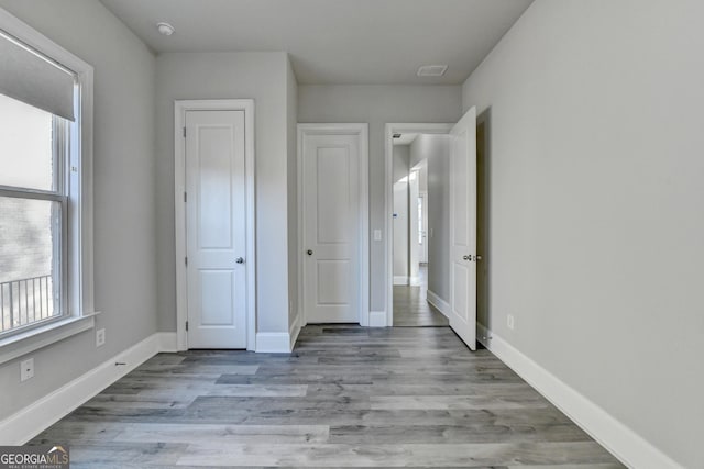 unfurnished bedroom with visible vents, baseboards, and wood finished floors