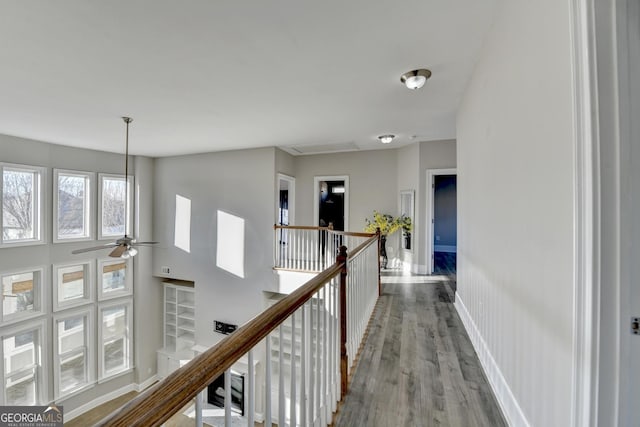 corridor with wood finished floors, an upstairs landing, and baseboards