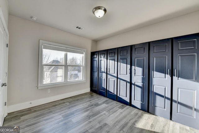 unfurnished bedroom with visible vents, baseboards, and wood finished floors