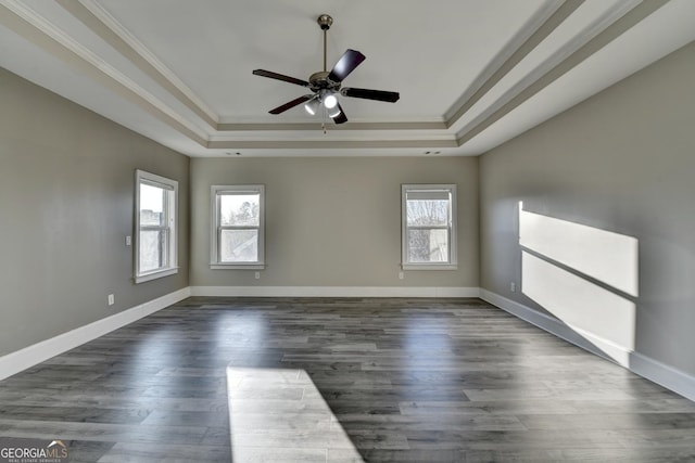 empty room with a raised ceiling, dark wood finished floors, and baseboards