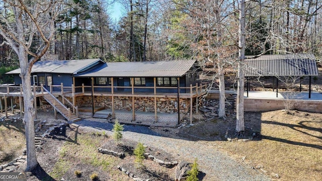 back of property featuring a deck, metal roof, stairway, and a chimney