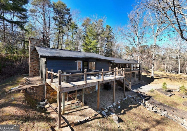 rear view of house featuring stairway, a chimney, metal roof, and a deck