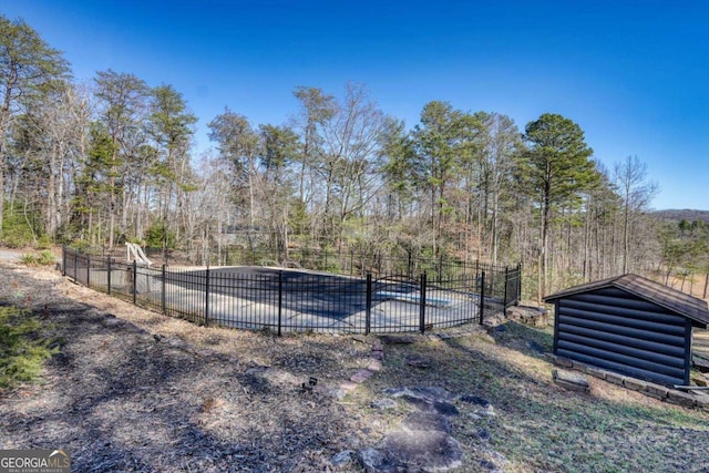 view of pool with a fenced in pool, fence, and a wooded view