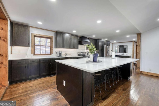 kitchen featuring stainless steel appliances, custom range hood, a large island, and dark wood-style floors