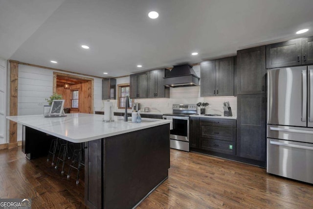 kitchen with stainless steel appliances, custom exhaust hood, dark wood finished floors, and a kitchen breakfast bar