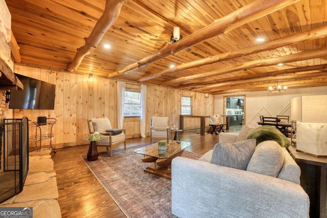 living room featuring wooden walls, wood ceiling, beamed ceiling, wood finished floors, and ceiling fan with notable chandelier