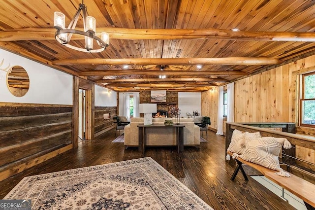 living area with wooden ceiling, dark wood-style flooring, beam ceiling, and a stone fireplace