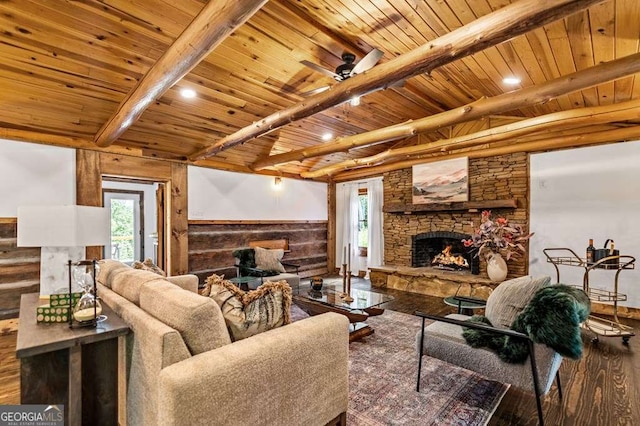 living area with a stone fireplace, a wainscoted wall, wood finished floors, wood ceiling, and beamed ceiling