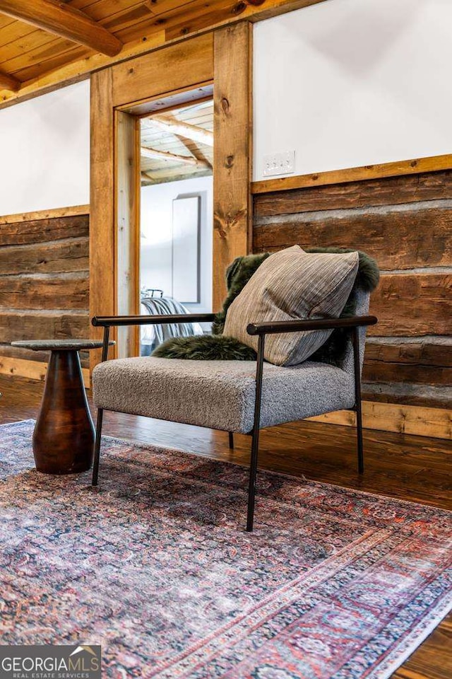 sitting room featuring wooden ceiling, beamed ceiling, wooden walls, and wood finished floors