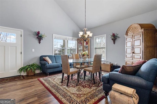 dining room featuring an inviting chandelier, high vaulted ceiling, and wood finished floors