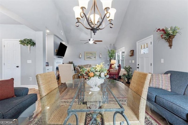 dining room with high vaulted ceiling, wood finished floors, and ceiling fan with notable chandelier