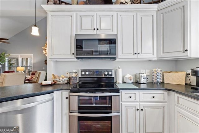 kitchen featuring decorative light fixtures, dark countertops, lofted ceiling, appliances with stainless steel finishes, and white cabinets