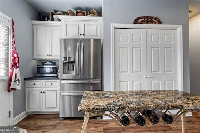 kitchen with a healthy amount of sunlight, dark countertops, stainless steel appliances, and dark wood-style flooring