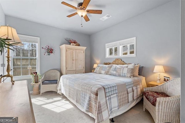 carpeted bedroom with ceiling fan and visible vents