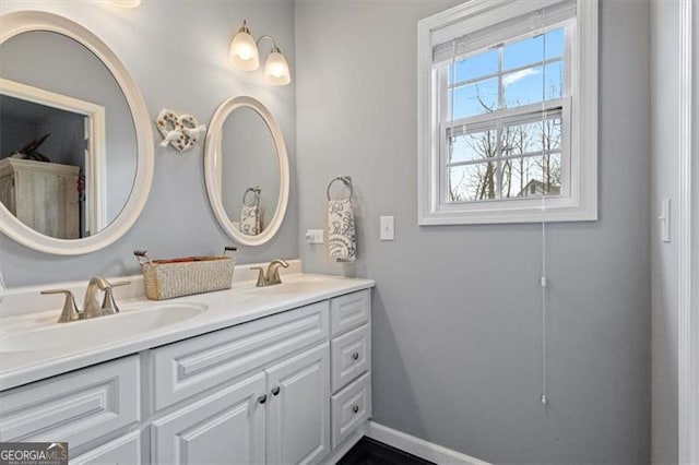 full bath with double vanity, a sink, and baseboards