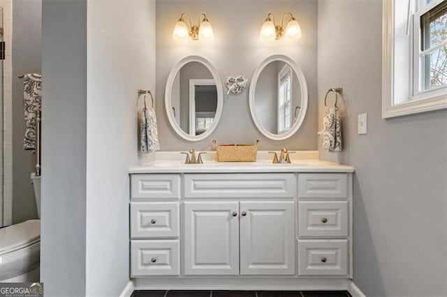 bathroom with double vanity, toilet, and baseboards