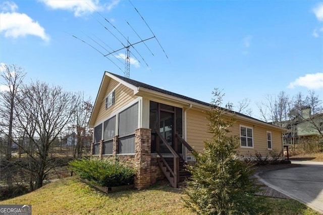 view of side of home featuring a yard, a sunroom, and driveway