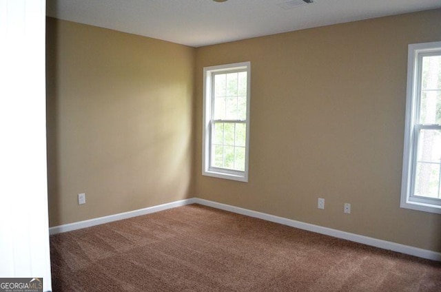 spare room with carpet flooring, visible vents, and baseboards