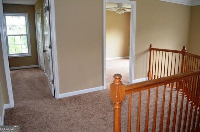 hallway featuring carpet floors, baseboards, and an upstairs landing