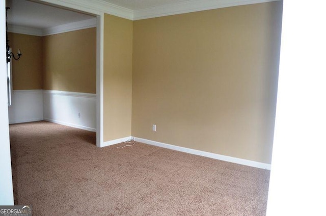 carpeted empty room featuring baseboards and crown molding