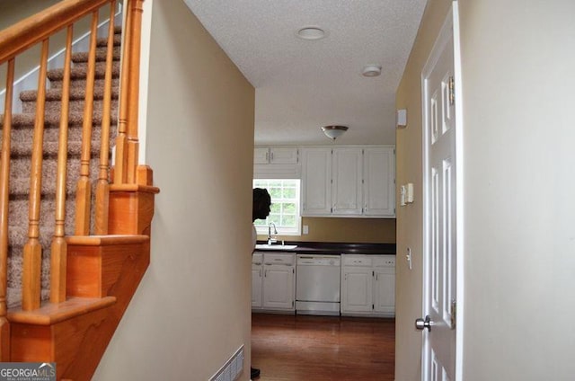 hallway with dark wood-type flooring, a sink, a textured ceiling, and stairs