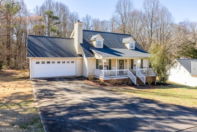 new england style home with an attached garage, a porch, concrete driveway, and roof with shingles