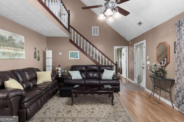 living area featuring visible vents, stairway, baseboards, and wood finished floors