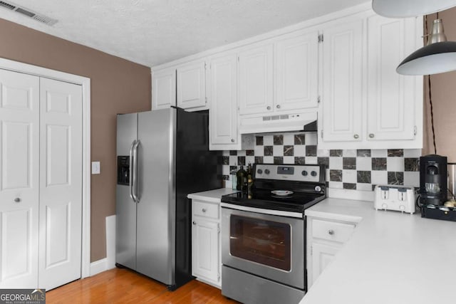 kitchen featuring visible vents, stainless steel appliances, light countertops, under cabinet range hood, and white cabinetry