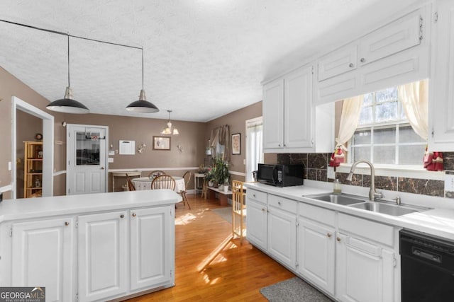 kitchen featuring light countertops, light wood-style floors, white cabinetry, a sink, and black appliances