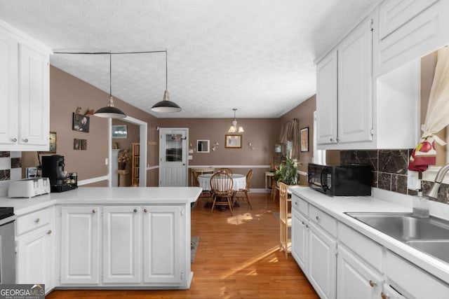 kitchen featuring light wood-type flooring, black microwave, white cabinets, and light countertops