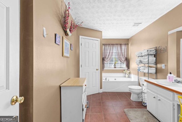 bathroom with tile patterned floors, toilet, vanity, a textured ceiling, and a bath