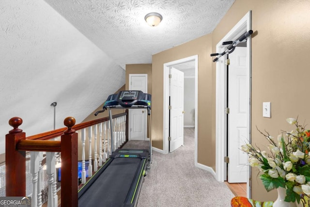 exercise area featuring carpet floors, lofted ceiling, a textured ceiling, and baseboards