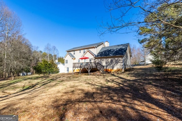 back of property featuring a chimney, a lawn, a deck, and stairs