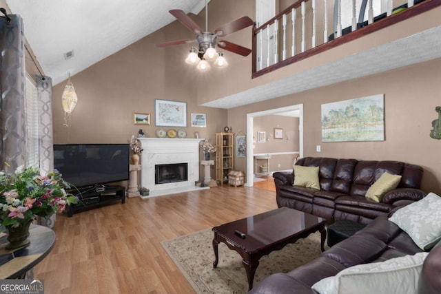 living area featuring vaulted ceiling, wood finished floors, a high end fireplace, and a ceiling fan