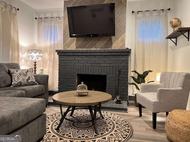 living area featuring light wood-type flooring and a brick fireplace