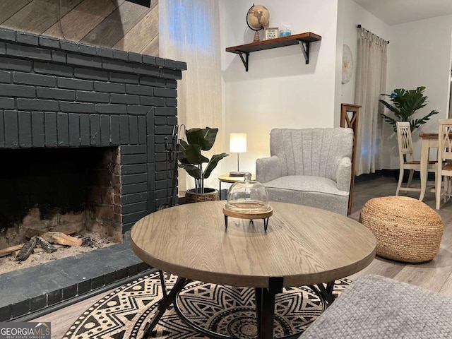 living area featuring a brick fireplace and wood finished floors