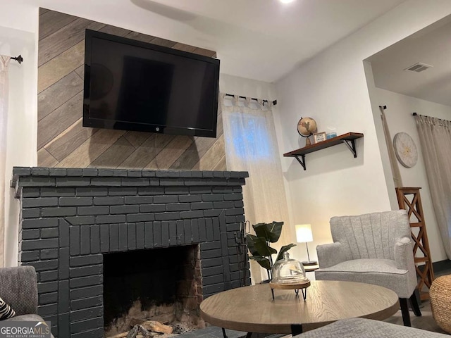 living area featuring a brick fireplace and visible vents