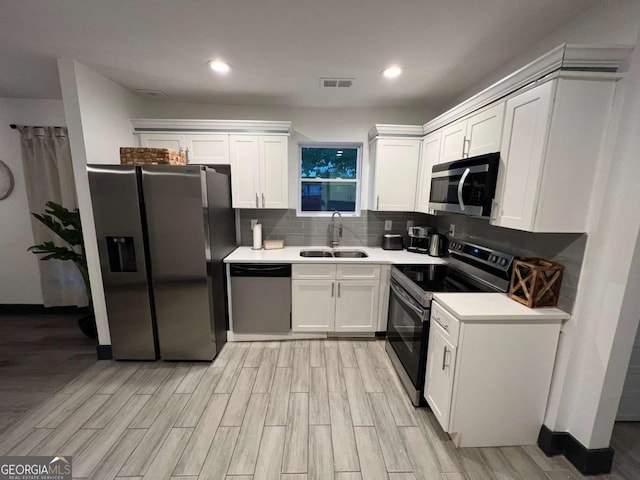 kitchen featuring stainless steel appliances, white cabinets, a sink, and decorative backsplash