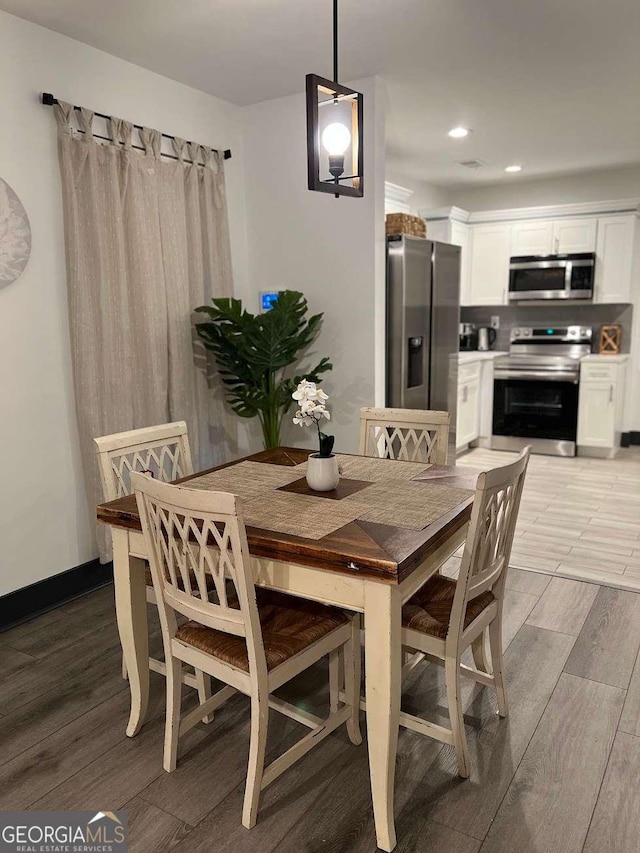 dining space featuring light wood finished floors, baseboards, and recessed lighting