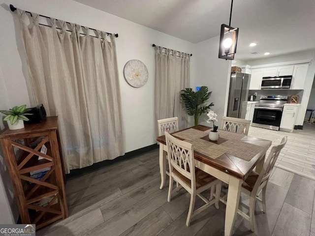 dining area featuring light wood finished floors, baseboards, and recessed lighting