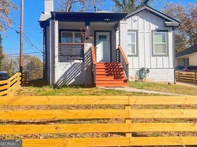 view of front facade featuring board and batten siding, fence, and a chimney