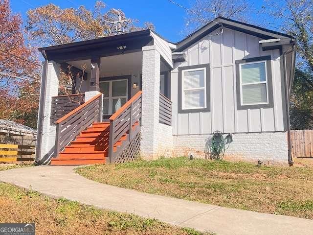 view of front of house with board and batten siding, covered porch, and a front lawn