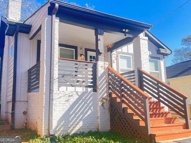 view of side of property with covered porch, a chimney, and stairs