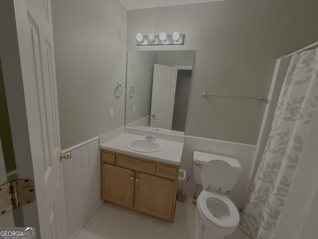 bathroom with a wainscoted wall, vanity, and toilet