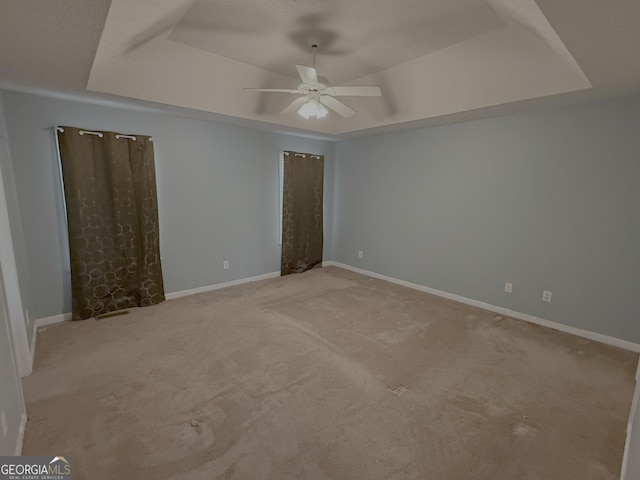 unfurnished bedroom with ceiling fan, carpet, baseboards, and a raised ceiling