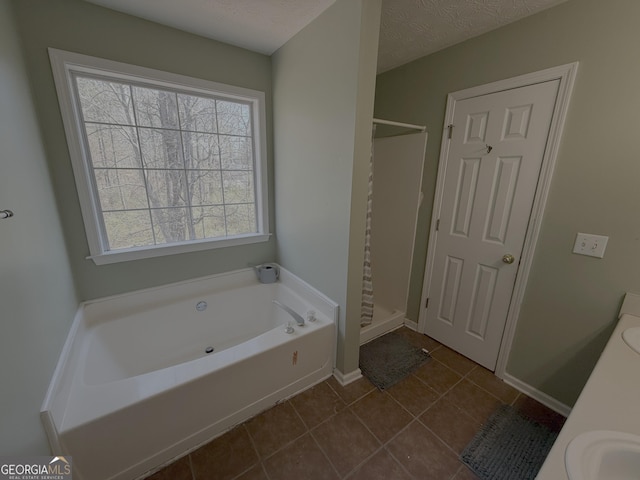 bathroom featuring a textured ceiling, baseboards, a bath, tile patterned floors, and a stall shower