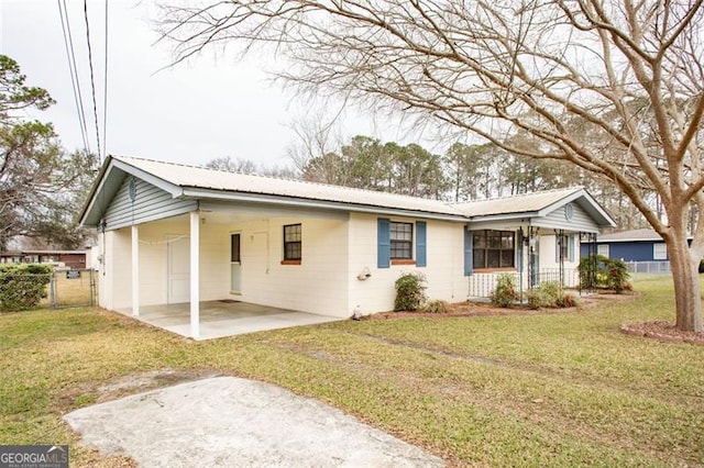 ranch-style house with metal roof, a carport, a front lawn, and fence